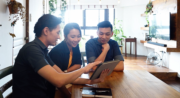 three people viewing and discussing something on a tablet